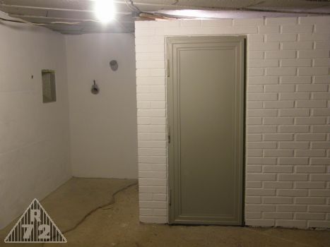 Pohled na prostor krycí střílny vchodu a uzavřenou místnost telefonistů s kopií původních dveří (klika prozatím není).