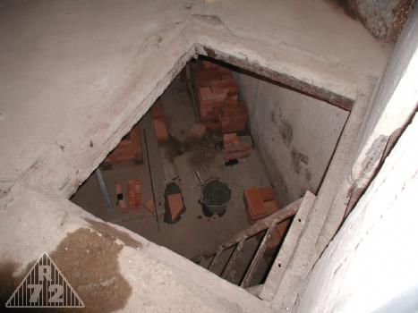 Průlez z levé kasematy do týlového patra. Na stěně pod průlezem bylo umístěno umyvadlo a nádrž na vodu. Vlevo dveře na WC.
