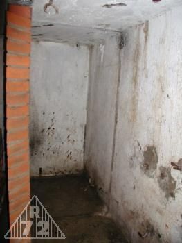 Pohled do prostor WC vzadu, v popředí byla umyvárna. Na pravé zdi je možno spatřit tmavý pruh - pozůstatek po betonové příčce, která oddělovala výše popsané prostory.