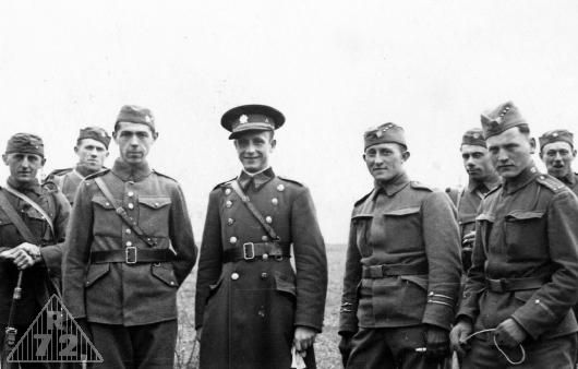 Skupina vojáků při výcviku. Zajímavá je uniforma vlevo stojícího důstojníka v polním stejnokroji a vpravo stojícím délesloužícím poddůstojníkem s typickým označením na rukávu.